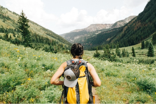 A woman with a backpack exploring fields and mountains